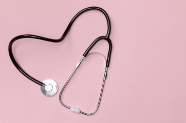 Stethoscope in shape of heart on pink table background, Good health from Doctor concept, Top view with copy space, Isolated on pink