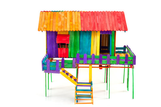 The house is made of toys from colorful popsicle sticks isolated on a white background.