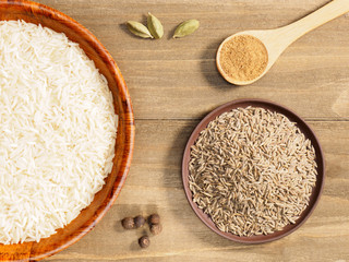 Rice, green cardamom, masala, cumin on brown wooden background. Indian cuisine, ayurveda, naturopathy, modern apothecary concept