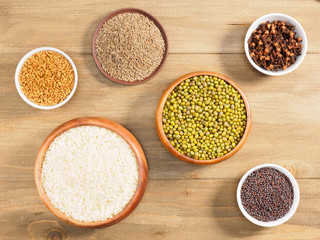 Rice, mung bean, mustard seeds, fenugreek, cumin, cloves on brown wooden background. Indian cuisine, ayurveda, naturopathy, modern apothecary concept
