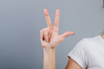 female hand in fist showing three fingers isolated over grey