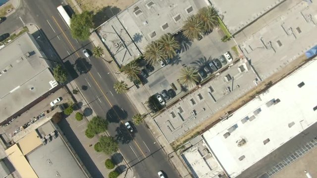 60 fps aerial shot of building tops, busses, cars, palm trees, and a backlot.