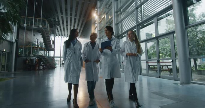 The doctors are discussing the diagnosis of a patient for the future advice for his treatment during walking in a hospital ward.