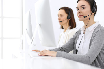 Call center. Beautiful woman receptionist sitting in headset at customer service office. Group of operators at work. Business concept