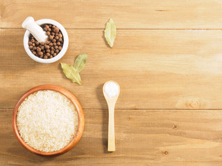 Rice, allspice, salt on brown wooden background. Indian cuisine, ayurveda, naturopathy, modern apothecary concept
