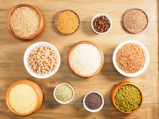 Rice, corn flakes, oat, mung bean, fenugreek, buckwheat, fennel, cumin, chick pea, cloves on brown wooden background. Indian cuisine, ayurveda, naturopathy, modern apothecary concept