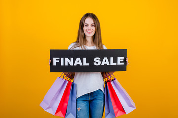 beautiful brunette woman with colorful shopping bags and copyspace text final sale sign isolated over yellow