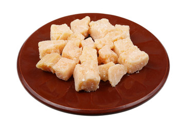 Heap of pieces of the elite matured cheese Parmesan two years old on ceramic plate isolated macro