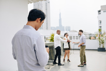 Young businesman checking social media on smartphone when comining to rooftop party