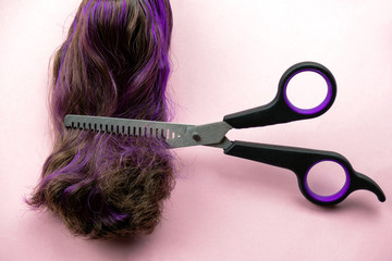 scissors trim unhealthy dry hair tips with fashionable violet coloring on pink background