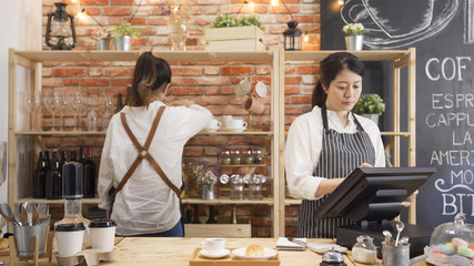 back view barista colleague choosing cup and taking down from shelf. elegant young lady waitress...