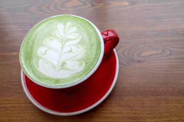 top view fresh matcha latte tea with latte art in a red ceramic cup on a vintage wooden table