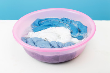 White and blue clothes washed with a basin with soap bubbles, close-up