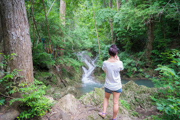 young cute hipster girl travelling at beautiful Erawan waterfall mountains  green forest hiking views at Kanchanaburi, Thailand. guiding  idea for female backpacker woman women backpacking