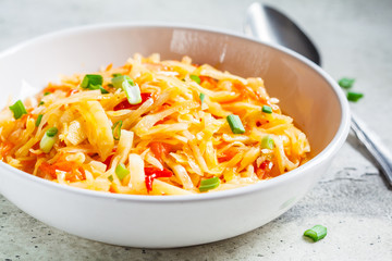Healthy cabbage and carrot salad in white bowl with green onions. Healthy fermented food concept.