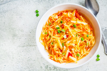 Healthy cabbage and carrot salad in white bowl with green onion, top view. Healthy fermented food concept.