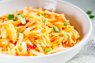 Healthy cabbage and carrot salad in white bowl with green onions. Healthy fermented food concept.