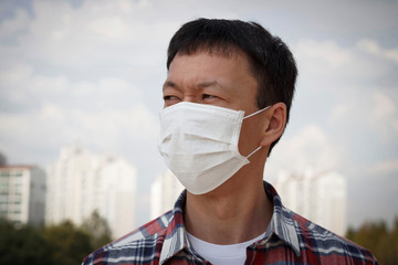The man in the mask on the background of the city, concept of air pollution