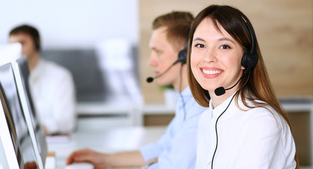 Call center. Group of diverse operators at work. Focus on beautiful asian woman in headset at customer service office. Business concept