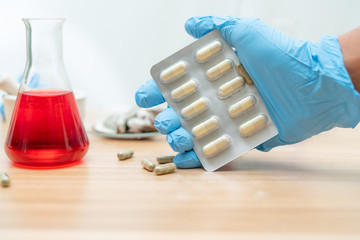 Capsule medicine in hand on blurred lab a room background,