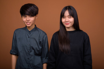 Young Asian lesbian couple together and in love against brown ba
