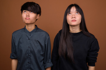 Young Asian lesbian couple together and in love against brown ba