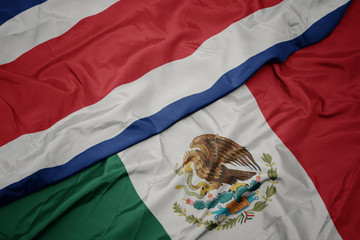 waving colorful flag of mexico and national flag of costa rica. macro