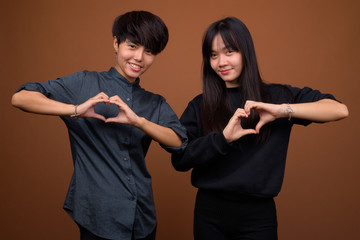Young Asian lesbian couple together and in love against brown ba
