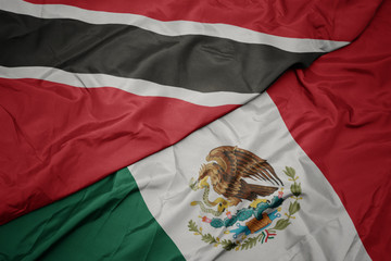waving colorful flag of mexico and national flag of trinidad and tobago. macro