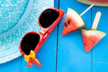 Watermelon and black glasses in the blue table on blue hat background,