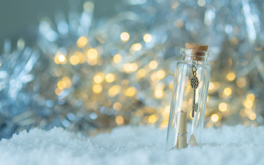 Small key in the bottle glass on the white snow with bokeh light,