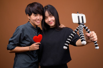 Young Asian lesbian couple together and in love against brown ba