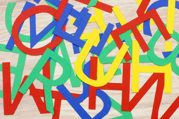 colorful jumbled letters, made of paper,  lying on wood