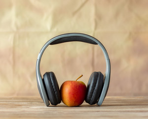 Red apple and earphone on the table with retro wall background,