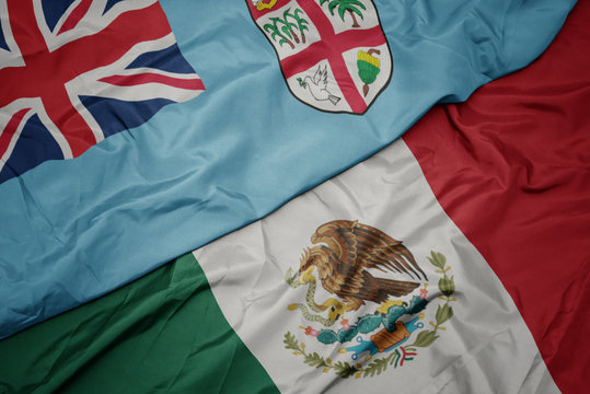 waving colorful flag of mexico and national flag of Fiji . macro