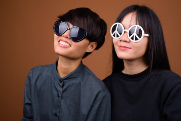 Young Asian lesbian couple together and in love against brown ba