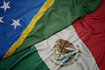 waving colorful flag of mexico and national flag of Solomon Islands . macro