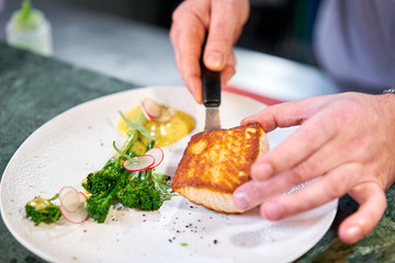 The chef serves the dish Salmon steak fillet and garnished with young broccoli. Restaurant menu, a series of photos of different dishes