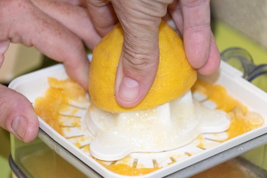 Mano con un lim&oacute;n en una exprimidor para obtener su jugo