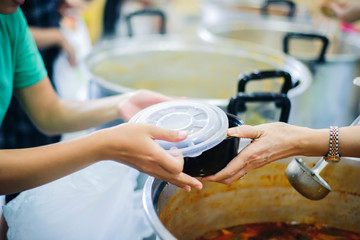 Volunteers are donating free charity food to homeless beggars: the concept of food needs in society.