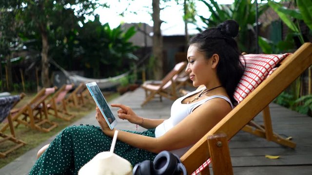 Young beautiful asian woman with tablet computer sitting in garden cafe