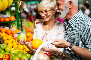 Mature couple shopping vegetables and fruits on the market. Healthy diet.