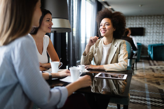 Successful attractive women friends chatting in cafe during coffee break