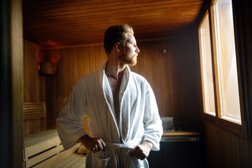 Handsome man relaxing in sauna in spa center