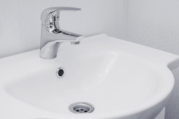 Modern sink with faucet in minimalist style. soft focus, copyspace. Running water from the tap on a white background. faucet with white sink