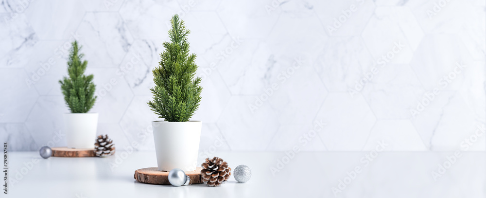 Aufkleber christmas tree with pine cone,decor xmas ball on wood log at white table and marble tile wall backgr