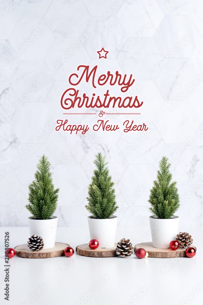 Poster Three christmas tree with pine cone and decor xmas ball on white table and marble tile wall background.clean minimal simple style.holiday still life mockup banner with space to adding text