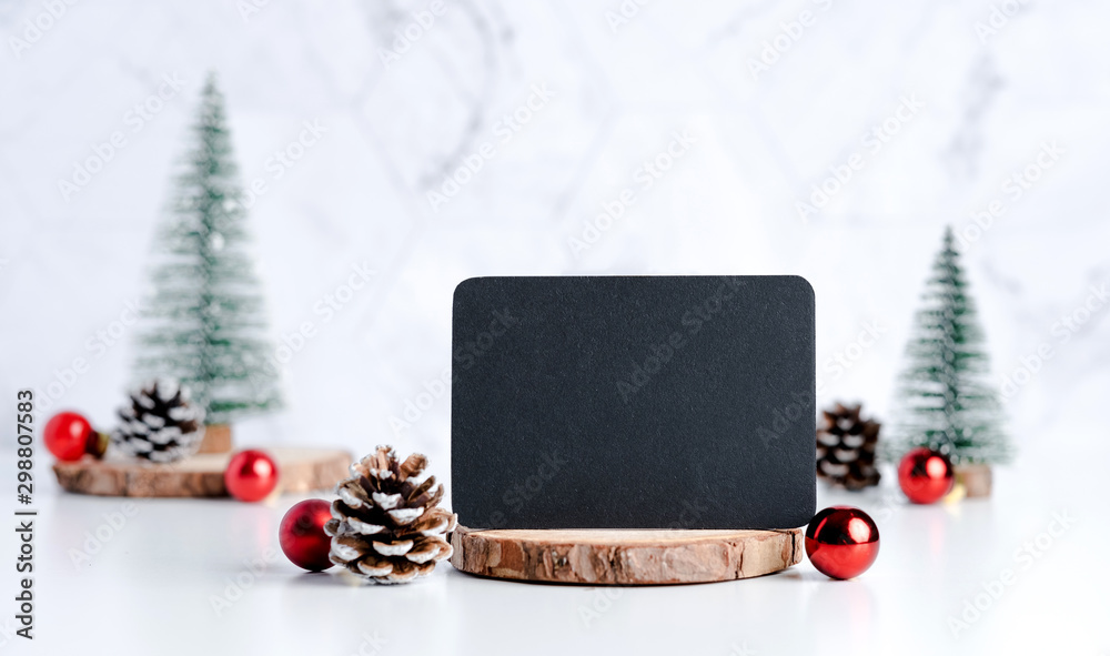 Poster blackboard with christmas tree with pine cone and decor xmas ball on white table and marble tile wall background.clean minimal simple style.holiday still life mock up banner with space to adding text