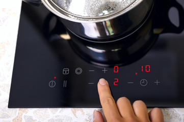 Woman hand includes modern induction stove