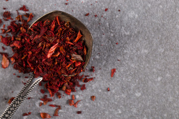 Crushed paprika in an iron spoon on a stone table. Copy space.